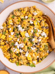 vegan Elote pasta salad in a large bowl with prtty wooden salad servers.