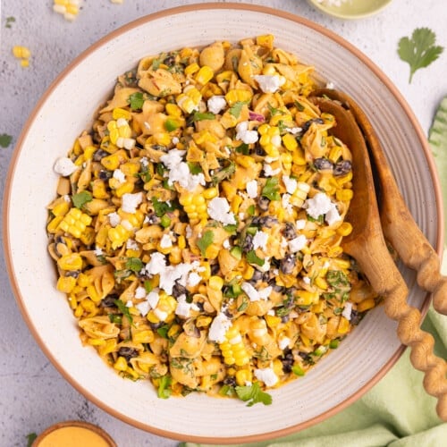 vegan Elote pasta salad in a large bowl with prtty wooden salad servers.