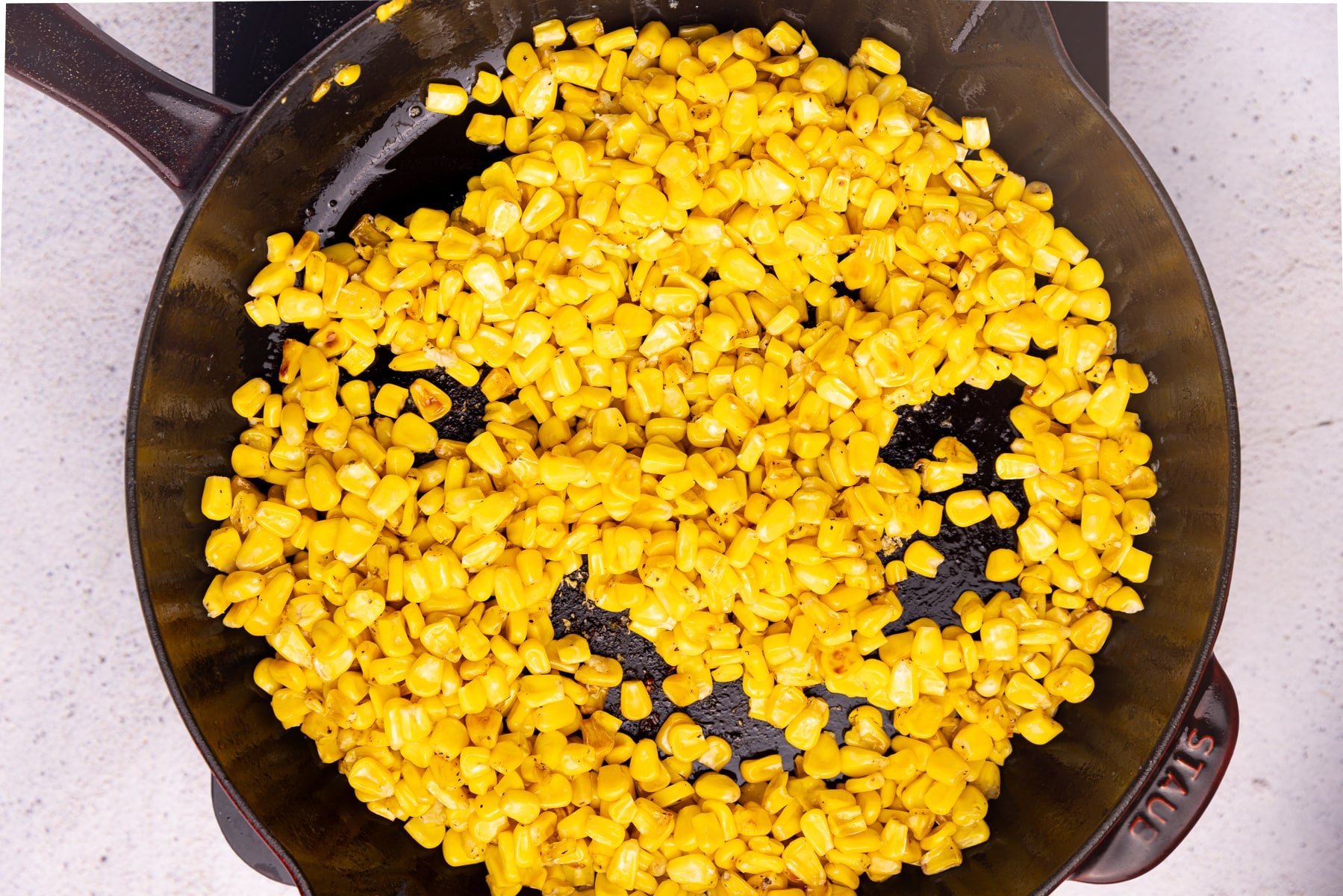 corn kernels cooking in a cast iron skillet. 