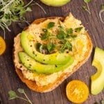 a piece of toast topped with spicy chickpea smash, avocado and microwgreens.