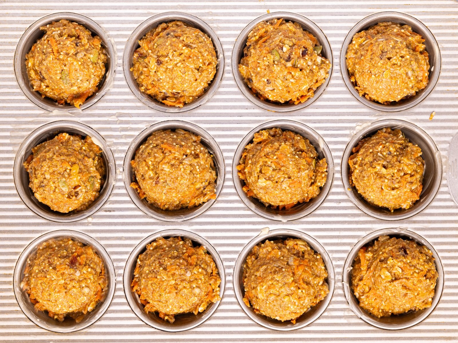 Uncooked muffins in a muffin pan. 