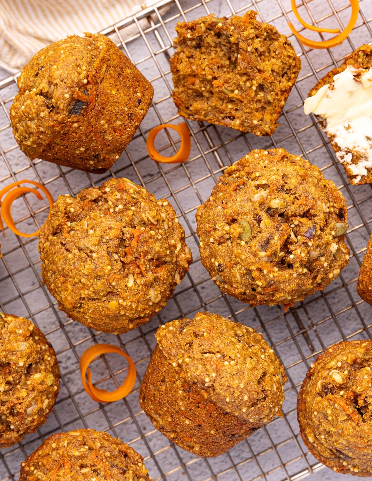 Vegan Morning Glory Muffins on a wire rack with some curly shreds of fresh carrot.