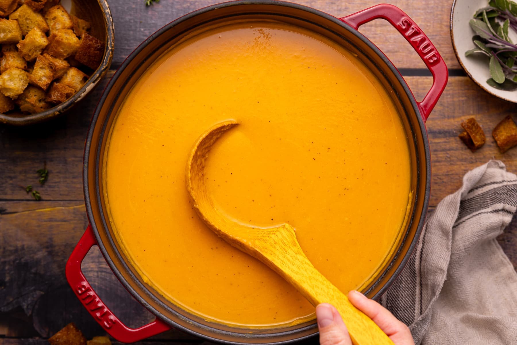 perfectly smooth vegan sweet potato soup being ladled out of a Dutch oven. 