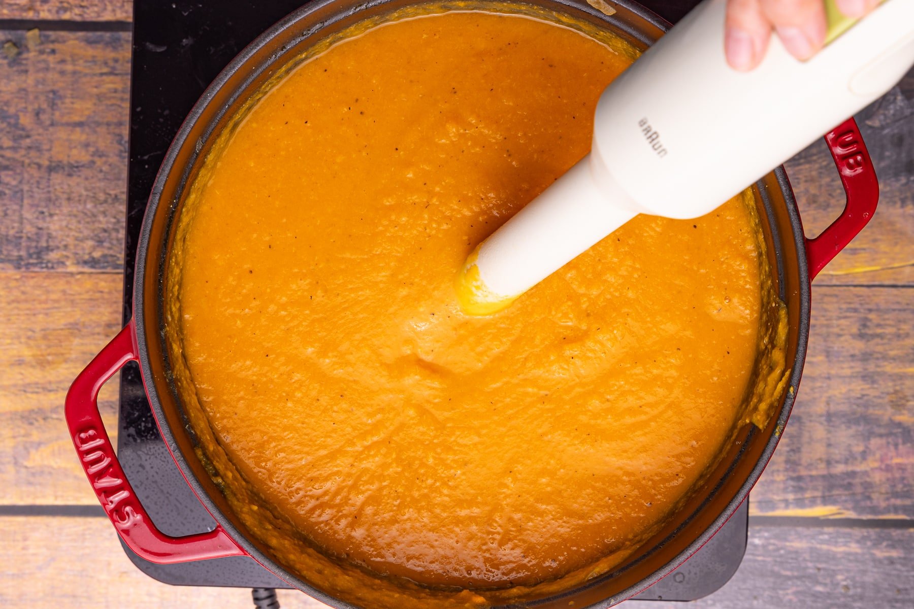 blending sweet potato soup with an immersion blender in a pan