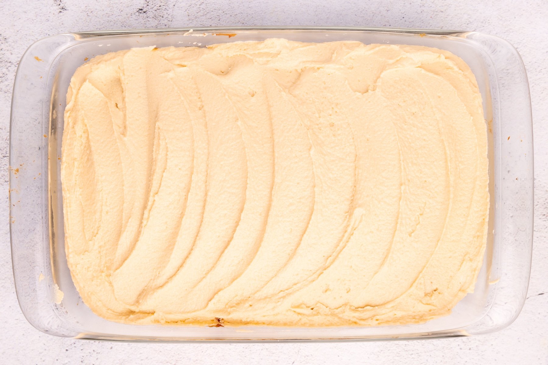 an iced cake in a rectangular glass baking dish. 