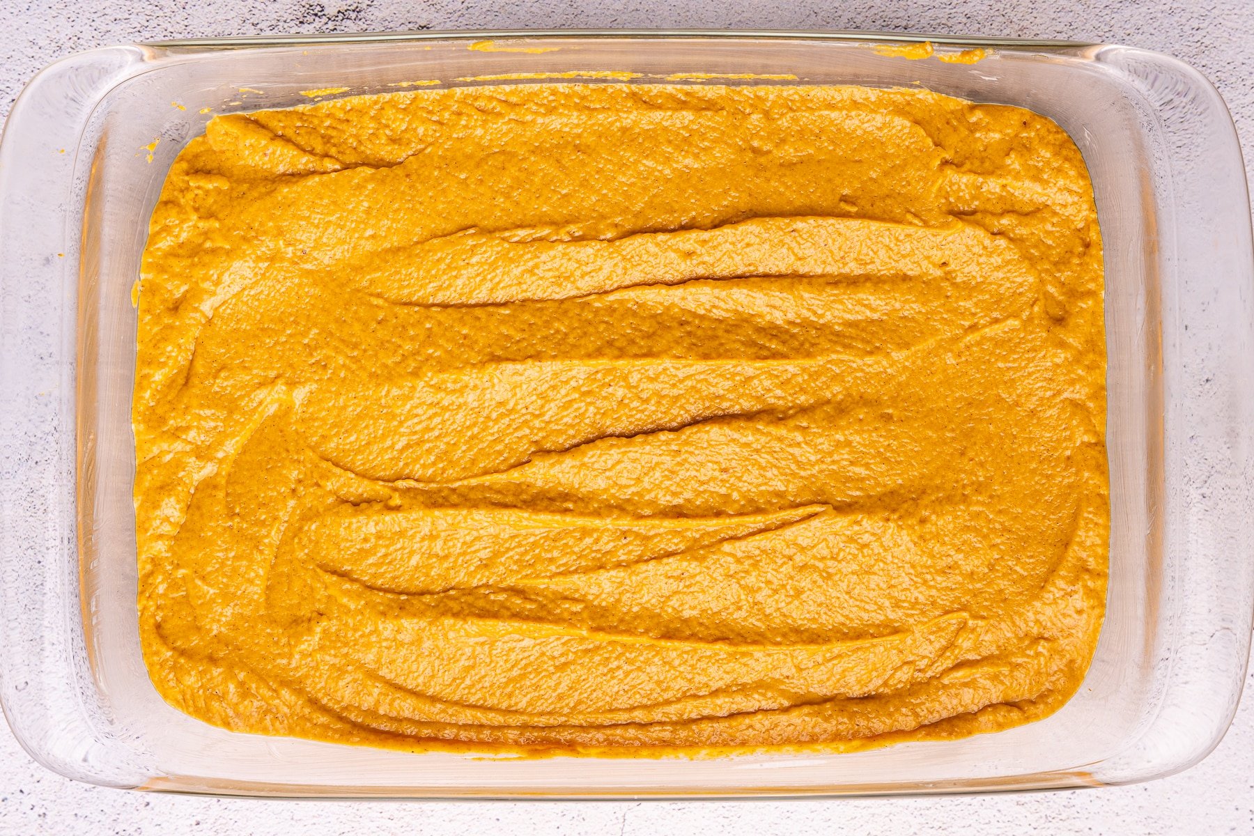 uncooked pumpkin cake in a glass baking dish