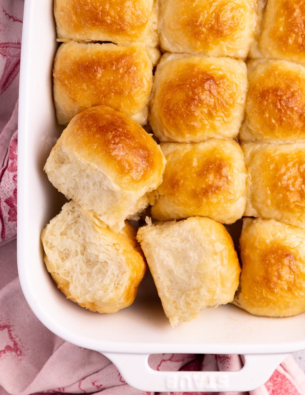 a dish of fluffy, golden vegan dinner rolls from above. 3 turned to the side so you can see the fluffy sides. 