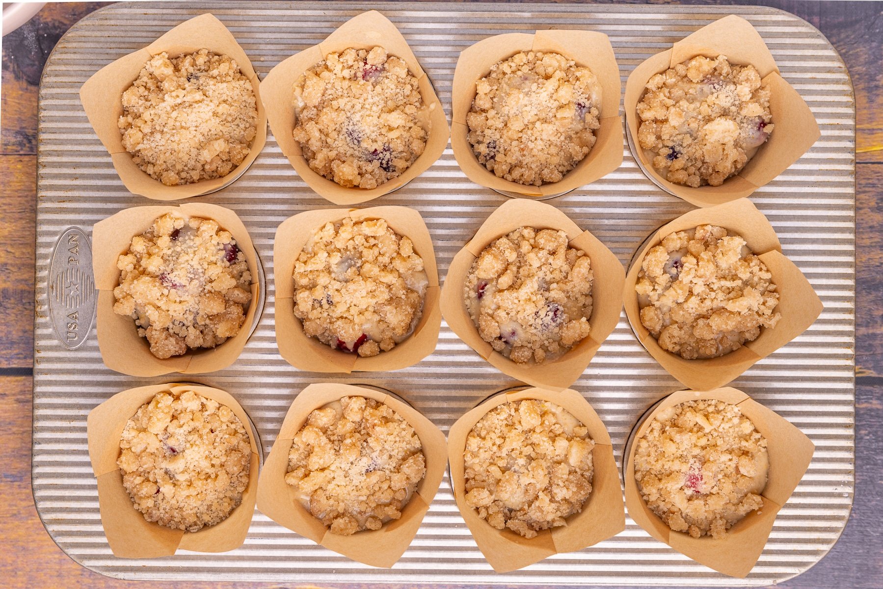 uncooked muffins topped with streusel in a muffin pan