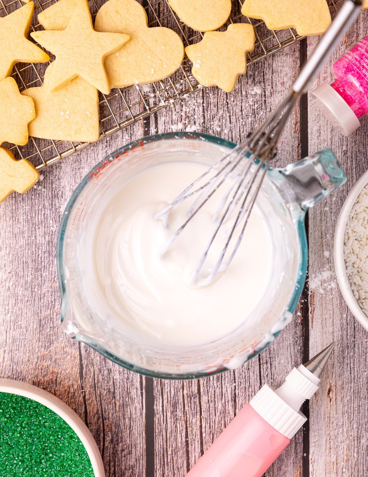 a jug full of white vegan sugar cookie icing with a whisk in it. 