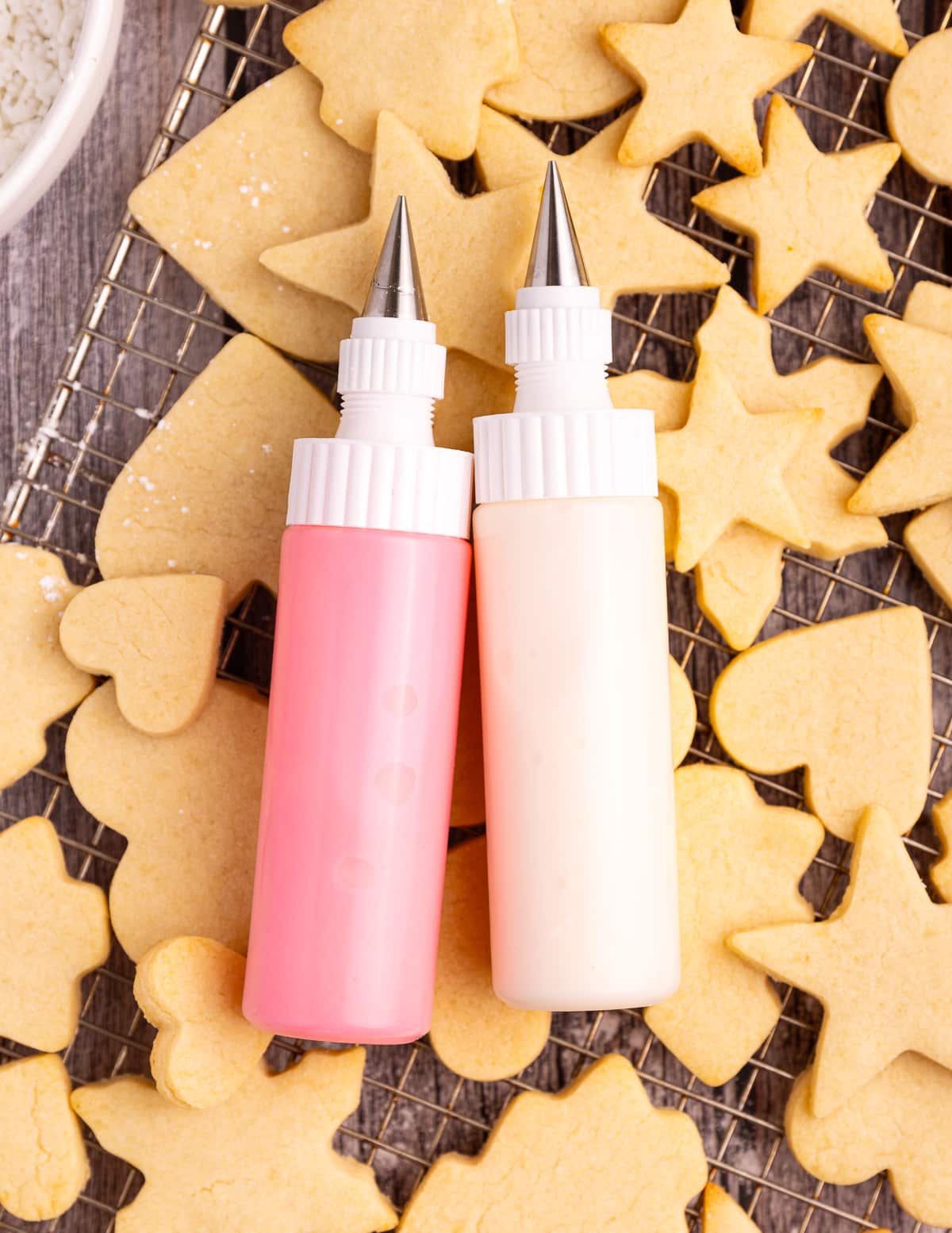 squeezy icing bottles with piping tips laid on top of sugar cookies