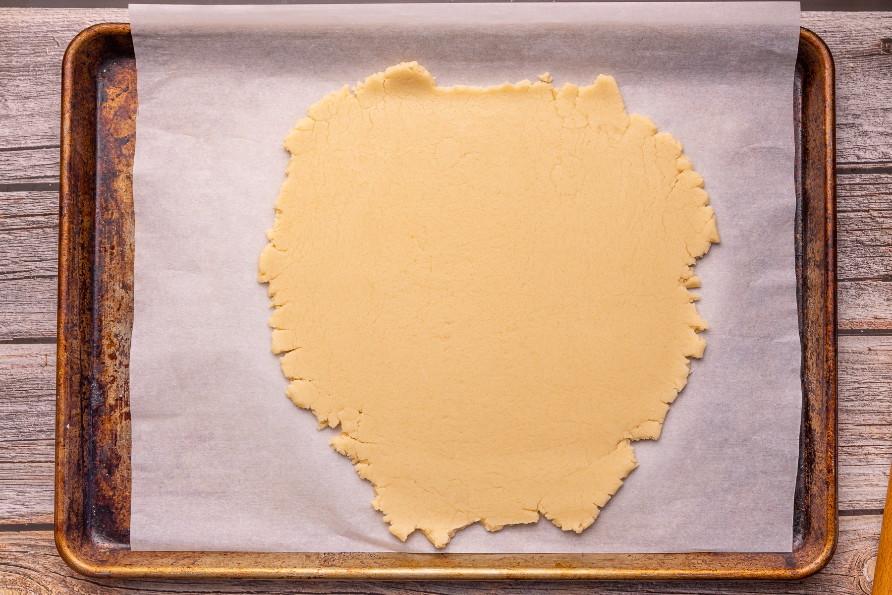 rolled out cookie dough on a parchment paper lined baking tray 