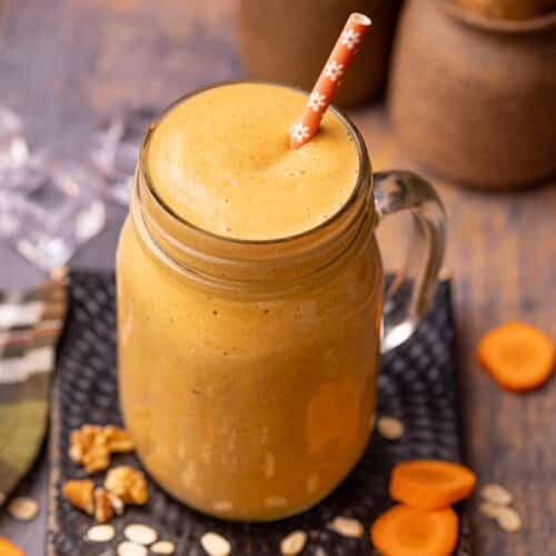 a glass of carrot cake smoothie with an orange straw