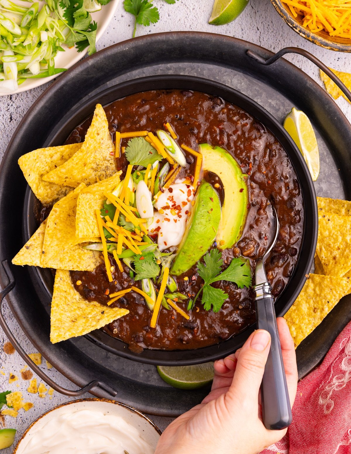 a bowl of instant pot bloack bean soup topped with tortilla chips, avocado, sour cream, cheese shreds, and cilantro. 