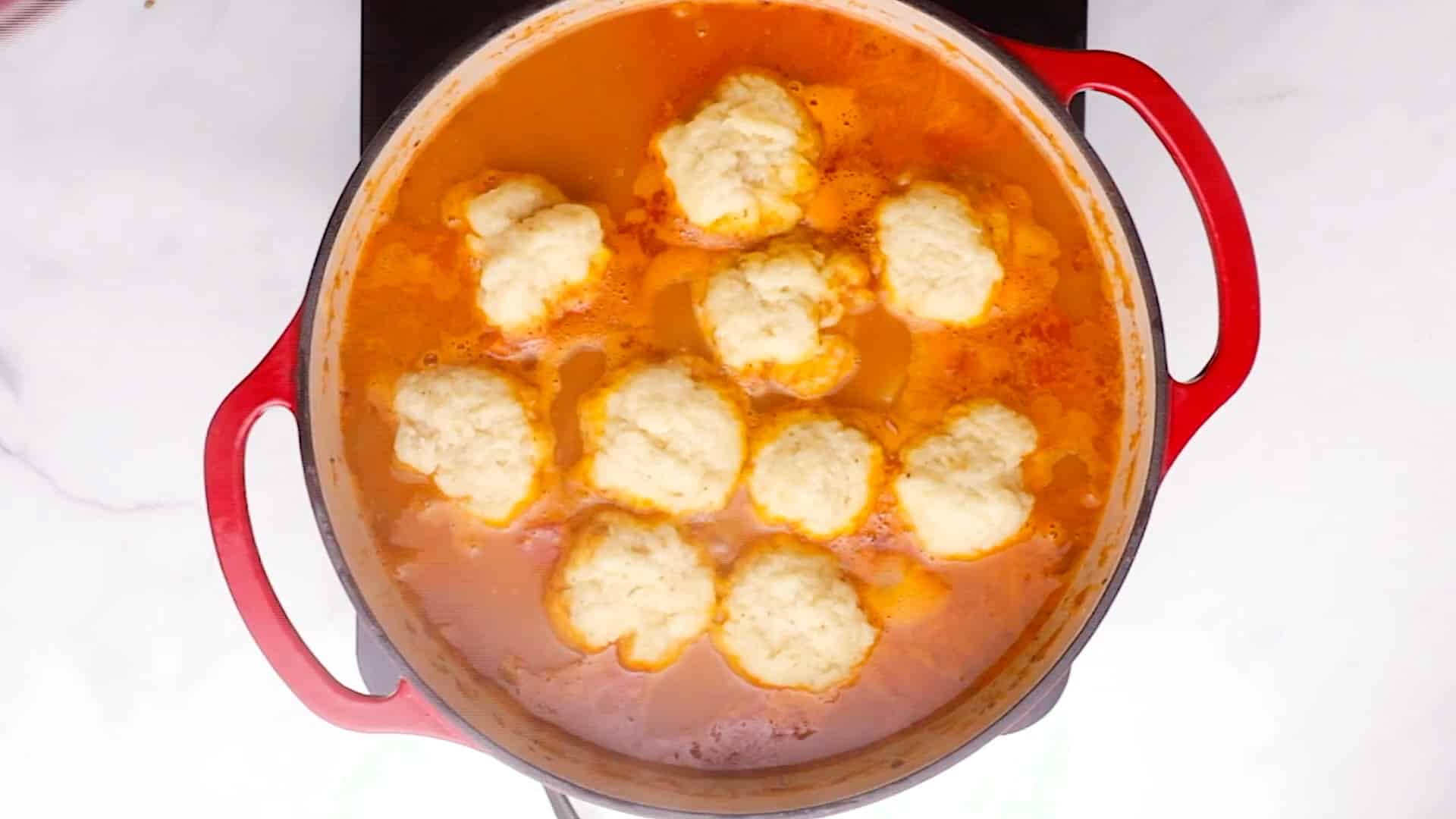 cooked fluffy dumplings floating on a pot of stew