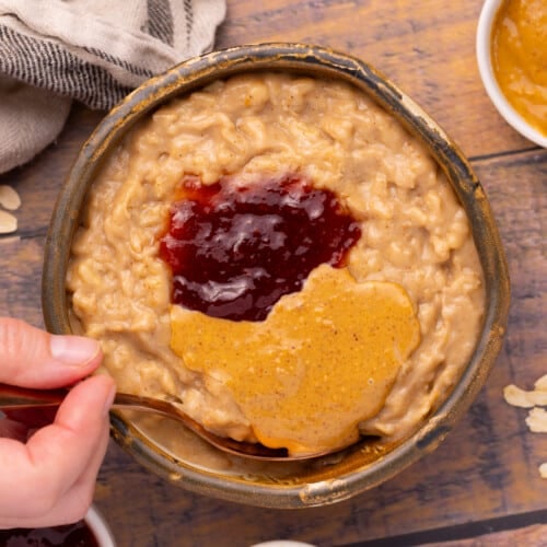 a bowl of peanut butter oatmeal topped with strawberry jam and peanut butter