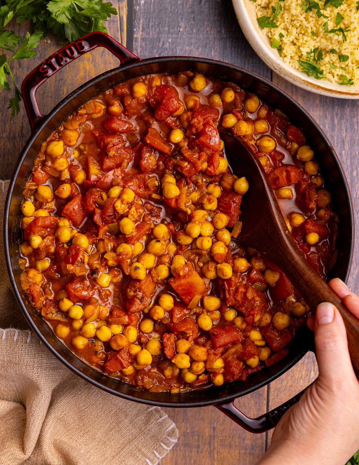 a pan of smoky spiced chickpeas in tomato sauce with a wooden spoon. 