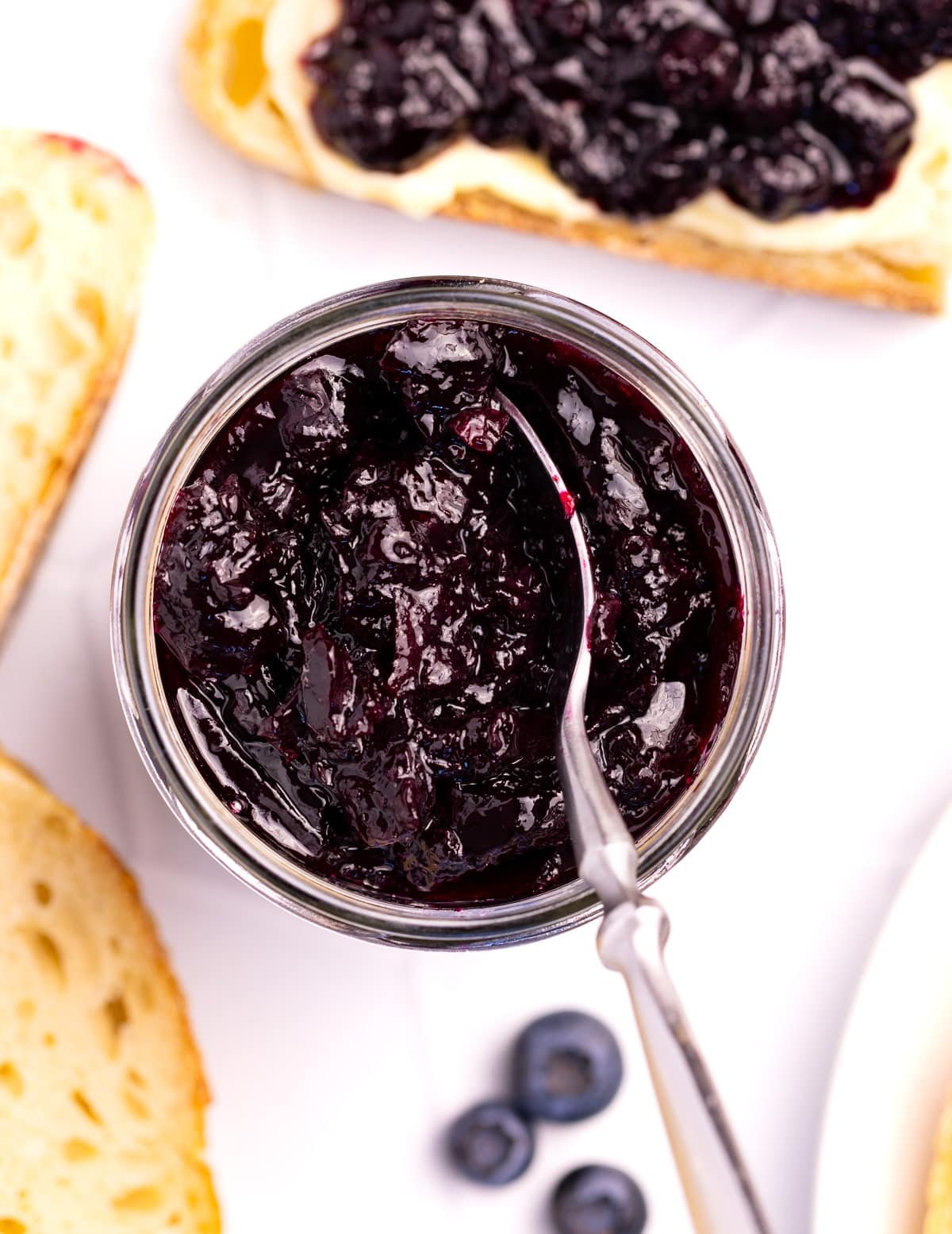an open jar of blueberry jam with a spoon in it.