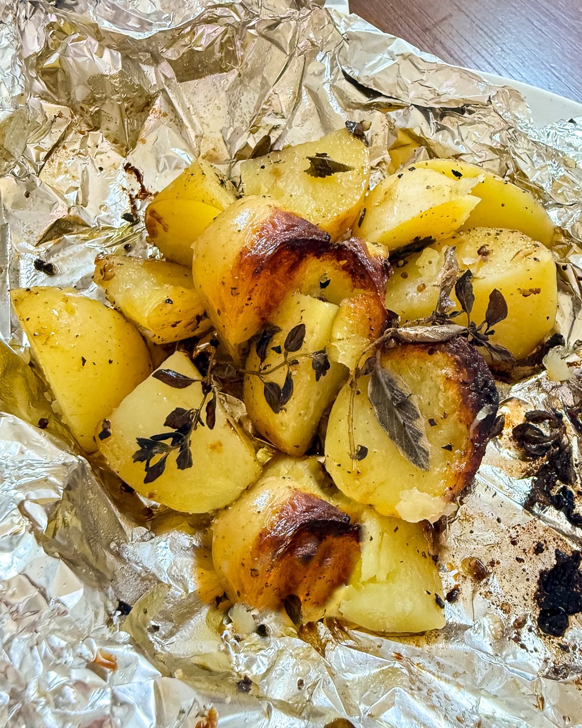 delicious looking soft and caramelized potatoes with herbs in a foil packet