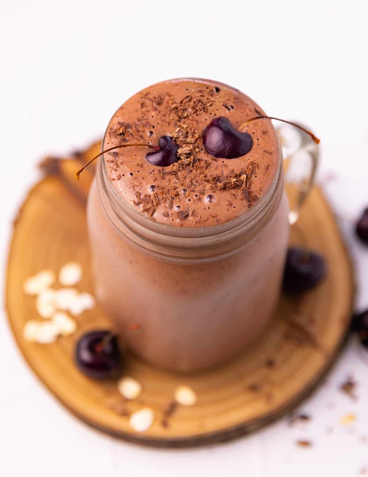 cherry chocolate smoothie in a glass, garnished with 2 fresh cherries.