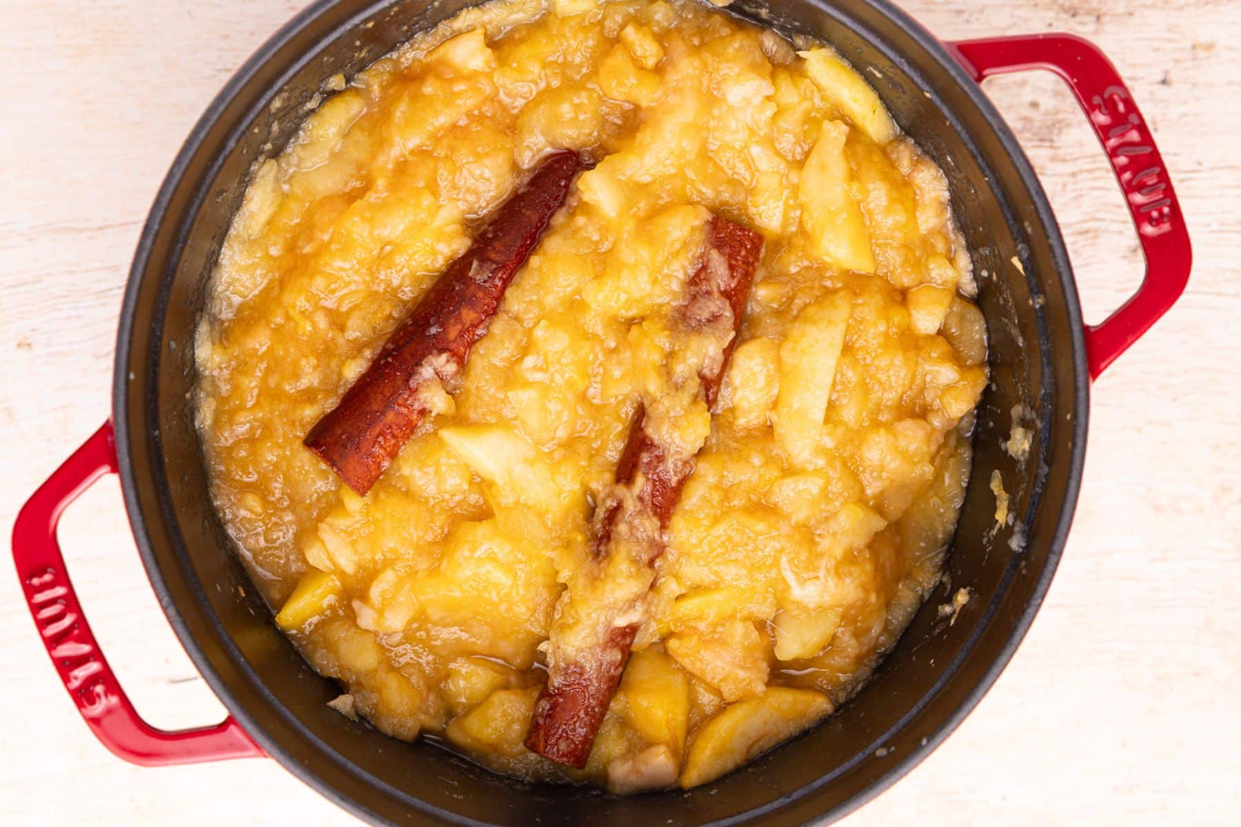 cooked apples and cinnamon sticks in a pan