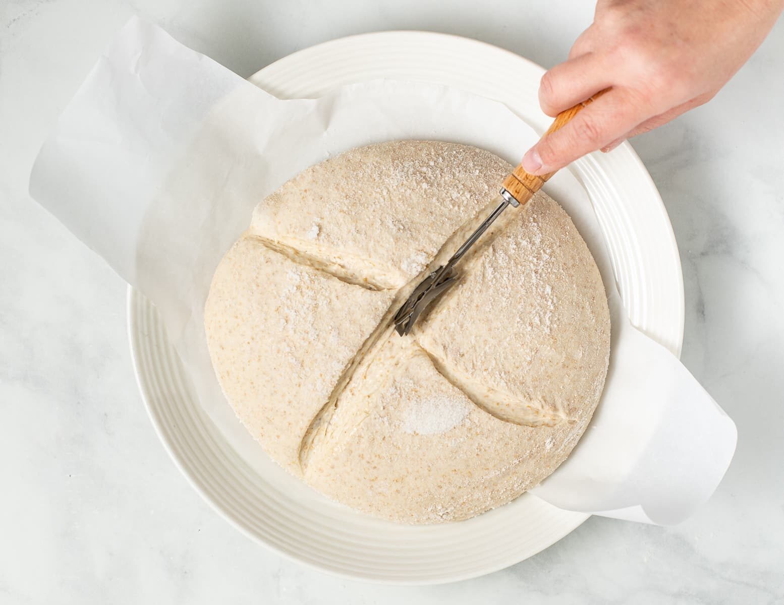 scoring a shaped loaf of bread with a lame