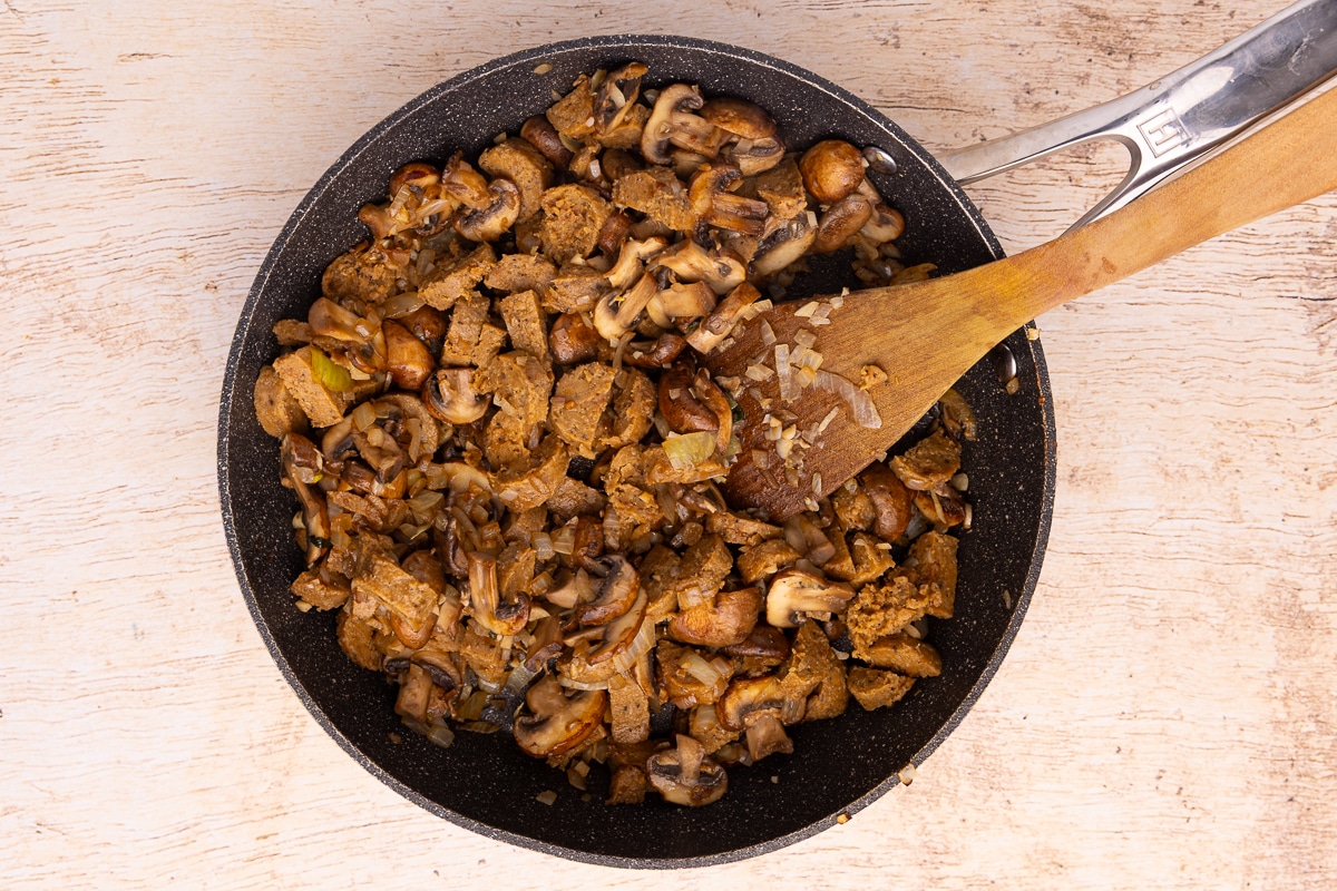 sautéed onion, garlic, mushrooms, and sausage in a pan.