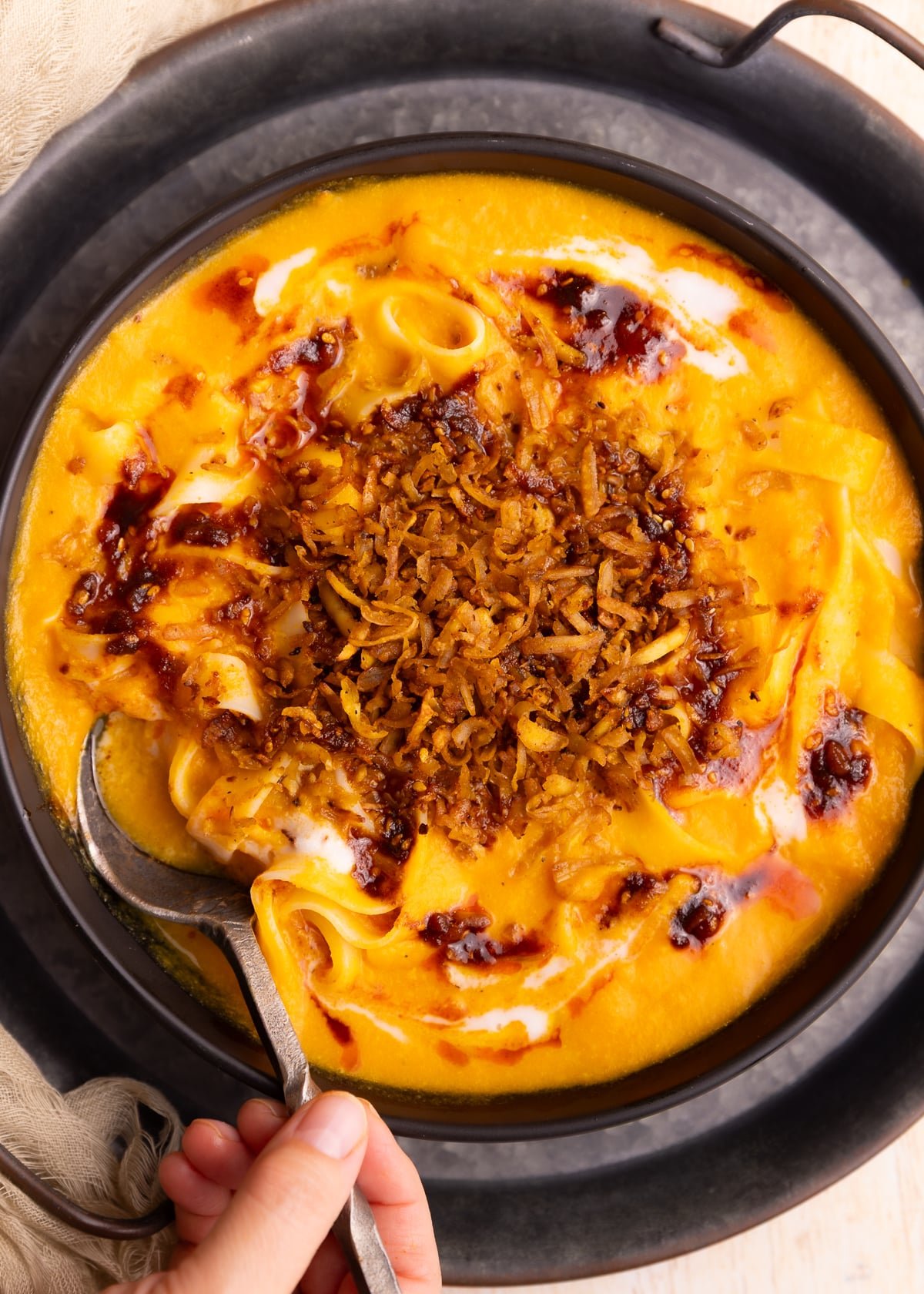 Creamy, luscious, silky carrot soup with slips of tender noodles, piles of chewy, crispy, spicy shredded tofu and drizzles of chili oil.