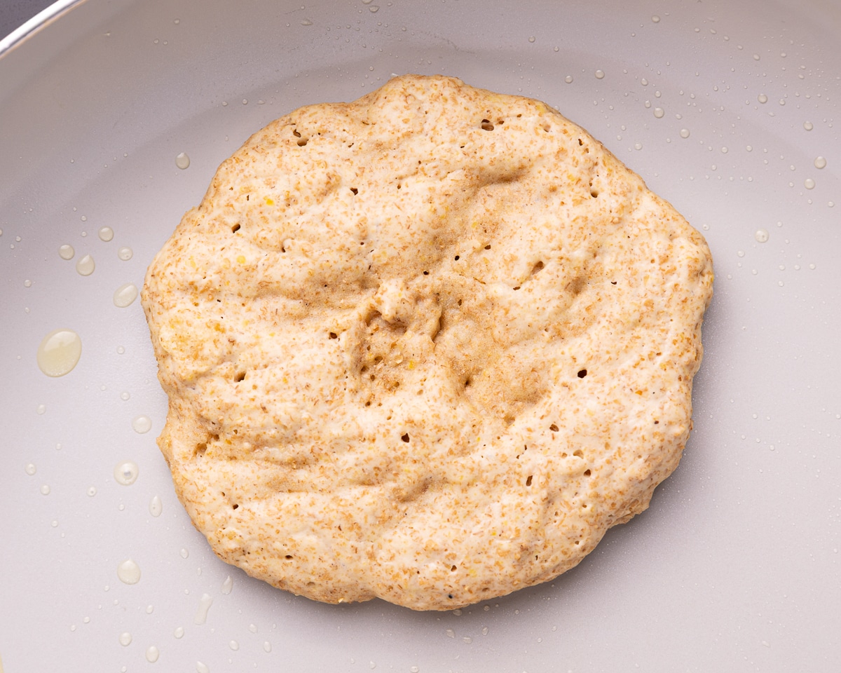 a partially cooked pancake with bubbles on the top