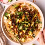 a hand holding a vegan brothy rice bowl