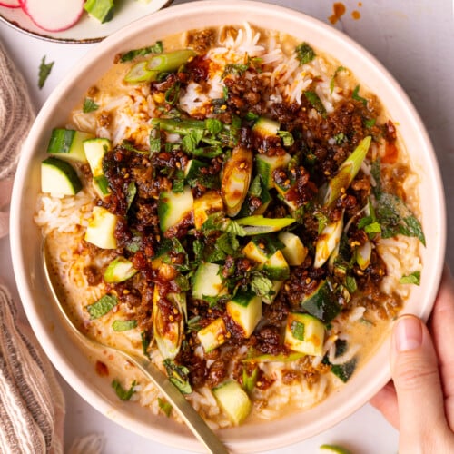 a hand holding a vegan brothy rice bowl