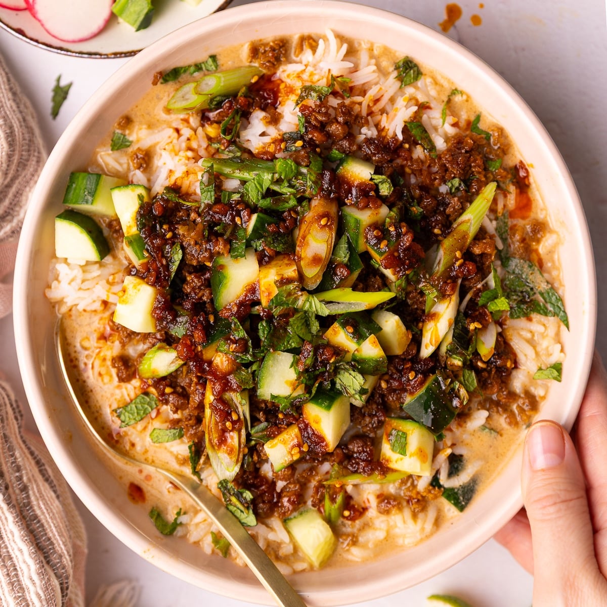 a hand holding a vegan brothy rice bowl