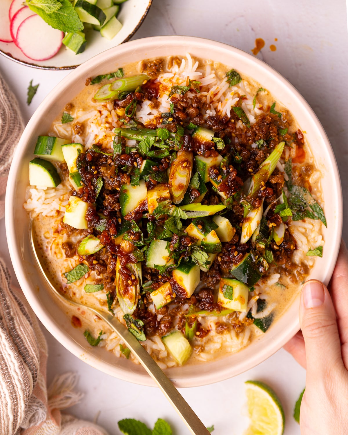 a hand holding a vegan brothy rice bowl