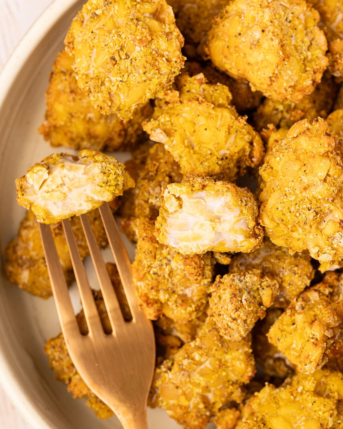 nutritional yeast tempeh in a bowl with one piece broken open so you can see the interior. 