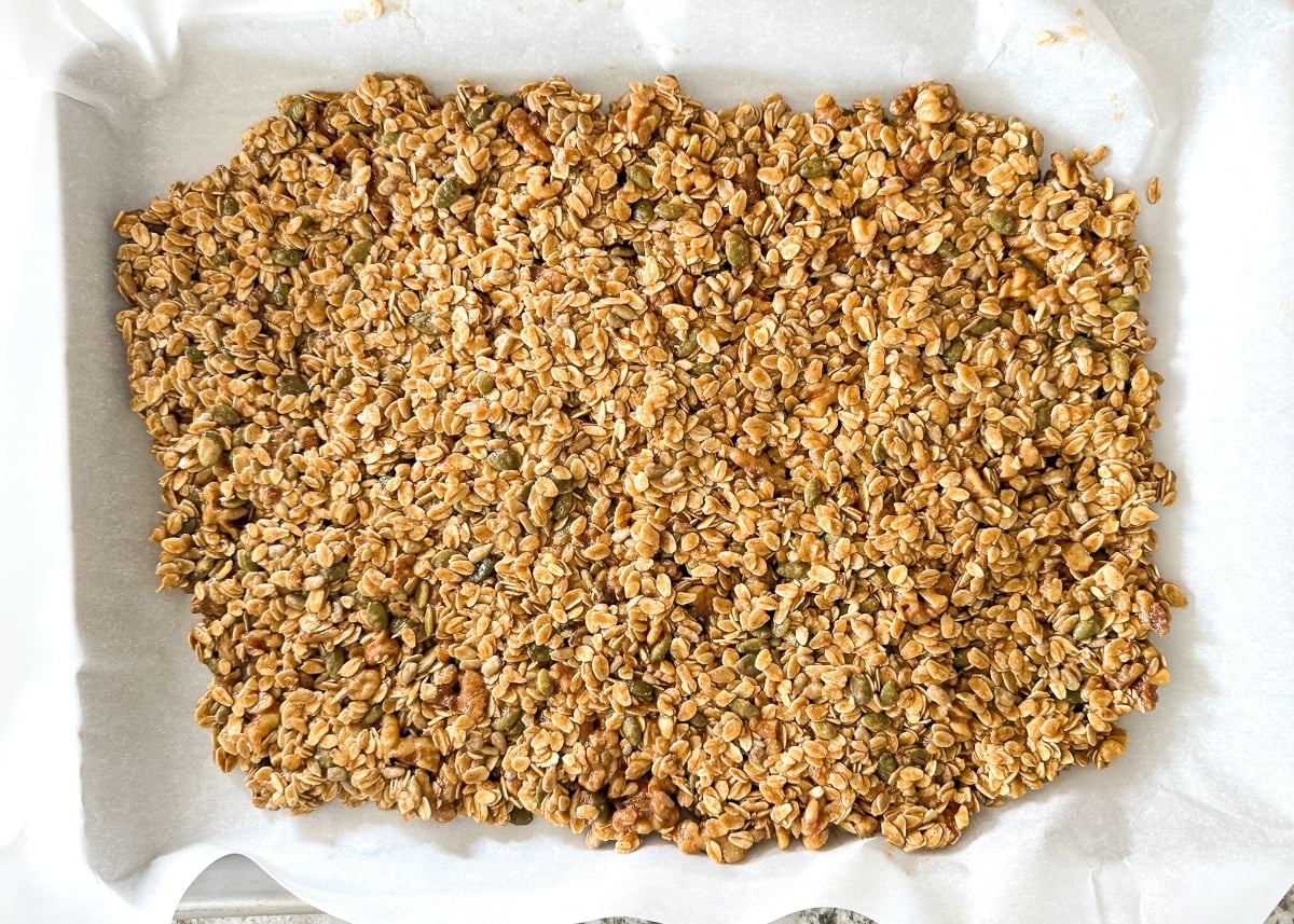 uncooked granola spread out on a baking tray
